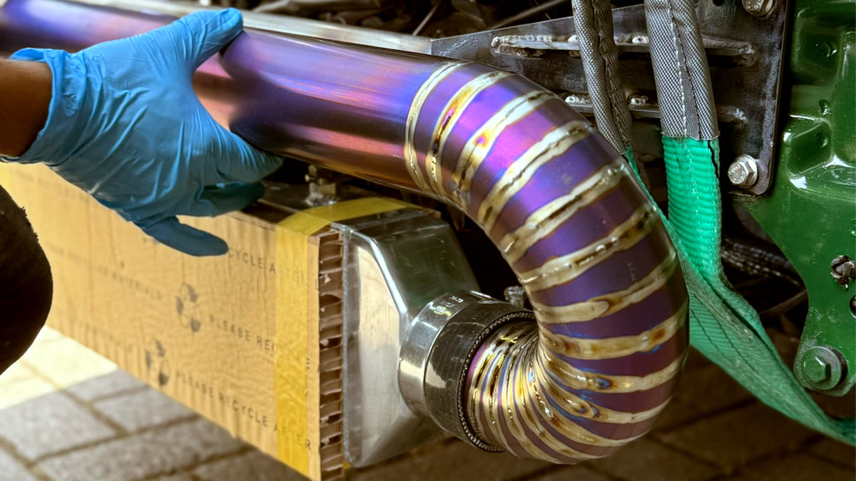 Gedetailleerde weergave van de lasnaden op een handgemaakte titanium pie-cut intercoolerbuis die handmatig wordt gepast.