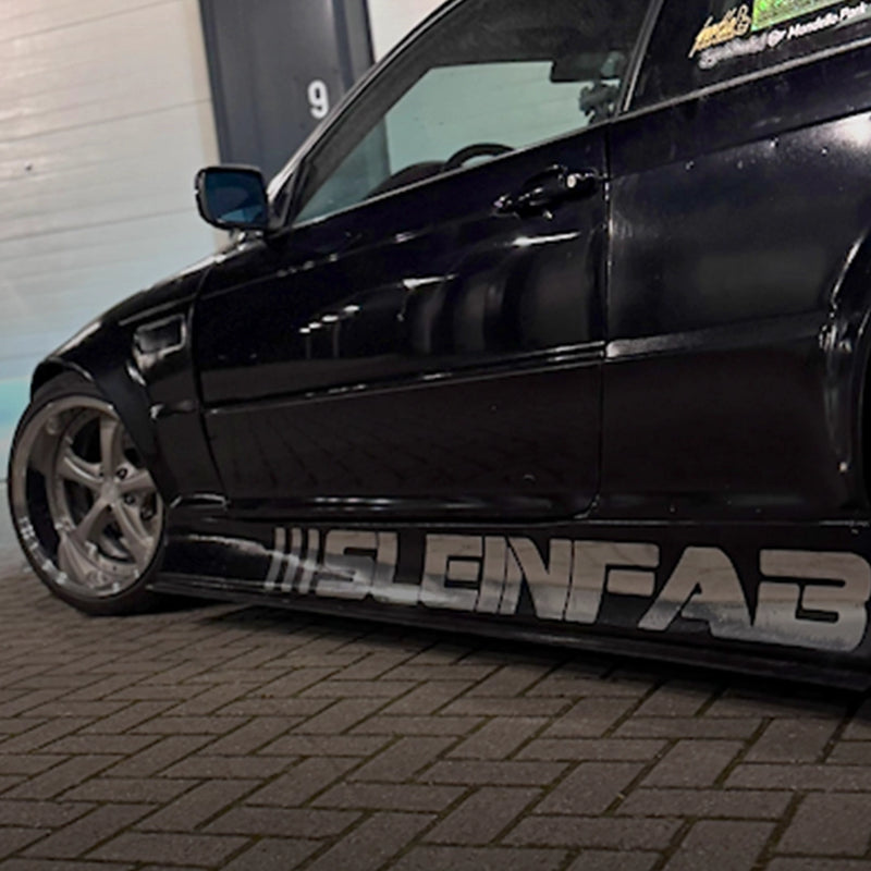 Zijprofiel van een verlaagde zwarte widebody BMW E46 coupé met een grote Stein Fab sticker op de sideskirt.